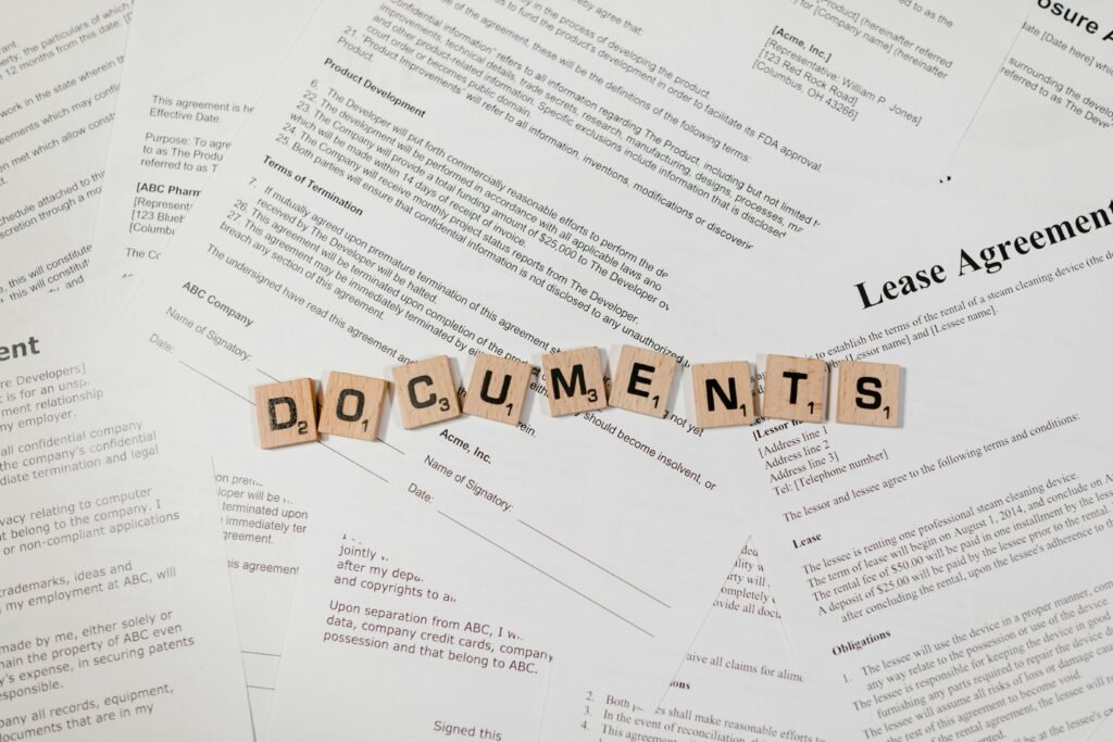 Top view of scrabble tiles spelling 'DOCUMENTS' on various contracts and agreements.